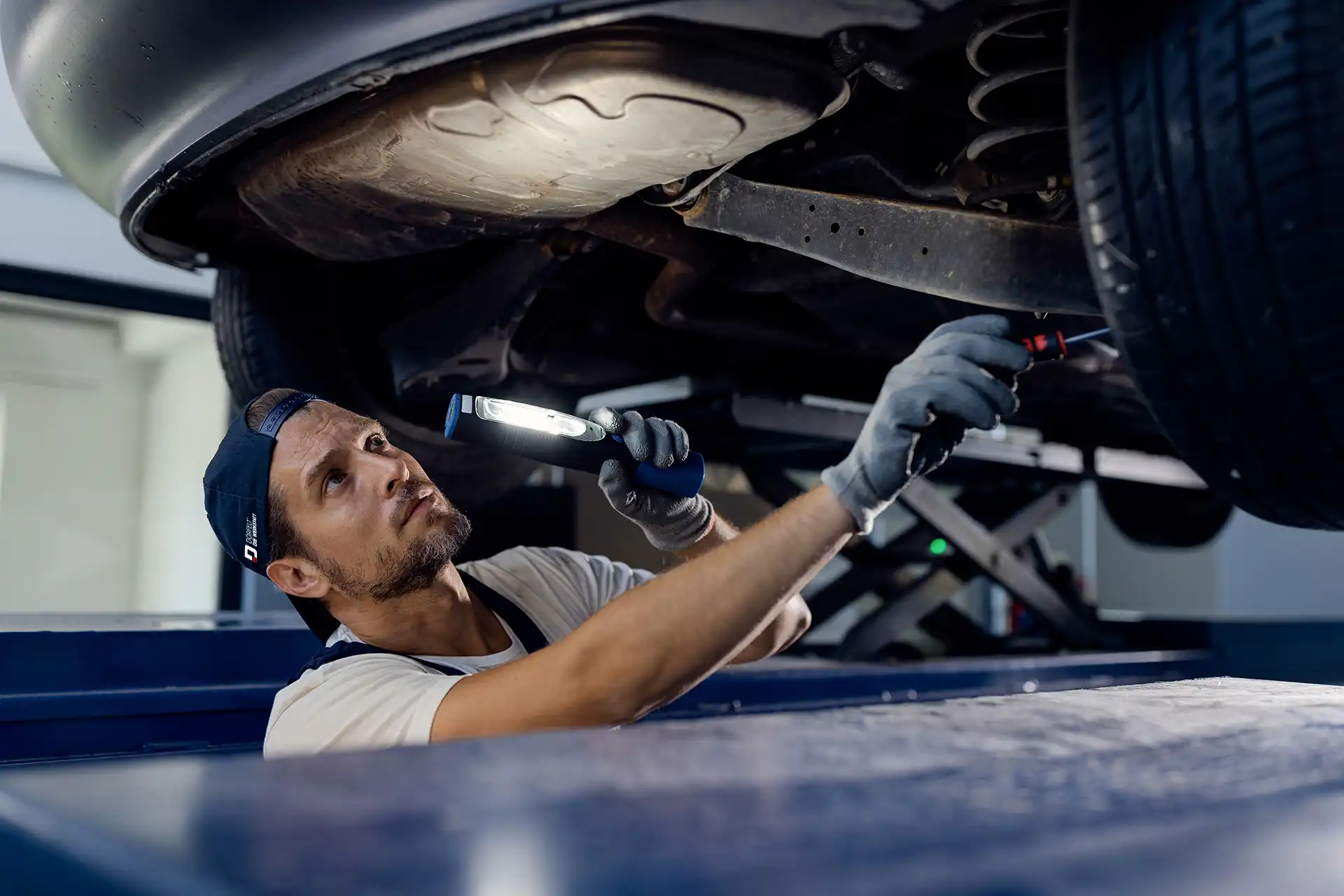 fahrzeugrahmen-ueberpruefen-auto-mechanic-examining-undercarriage-car-with-flashlight-repair Nach größeren Unfällen prüfen wir den Fahrzeugrahmen auf unserer Richtbank und setzen ihn millimetergenau instand.